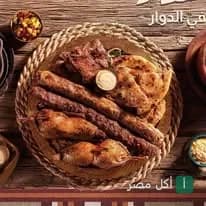 طبق مشويات شرقي متنوع يضم كفتة وقطع دجاج على طاولة خشبية في مطعم الدوار بطنطا.