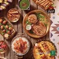 تشكيلة متنوعة من المشاوي والأطباق الشرقية على طاولة خشبية في مطعم الدوار بطنطا.