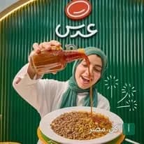 فتاة ترتدي حجاب أخضر تصب صلصة الكشري على طبق في مطعم كشري عدس بطنطا.