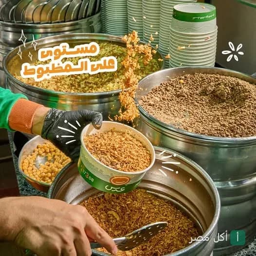 موظف يغرف البصل المقرمش في علبة كشري داخل مطعم كشري عدس في منطقة سعيد بطنطا.