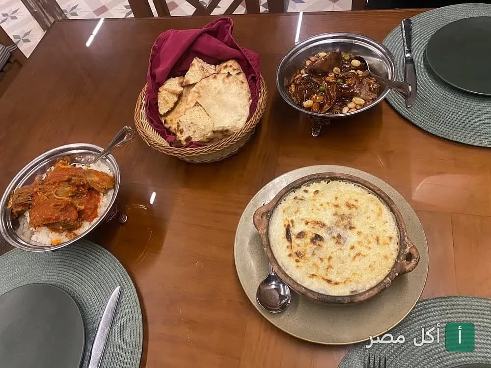 مائدة طعام متنوعة تضم أطباقاً شرقية وطاجن بالبشاميل في مطعم زيارة المعز بالقاهرة.