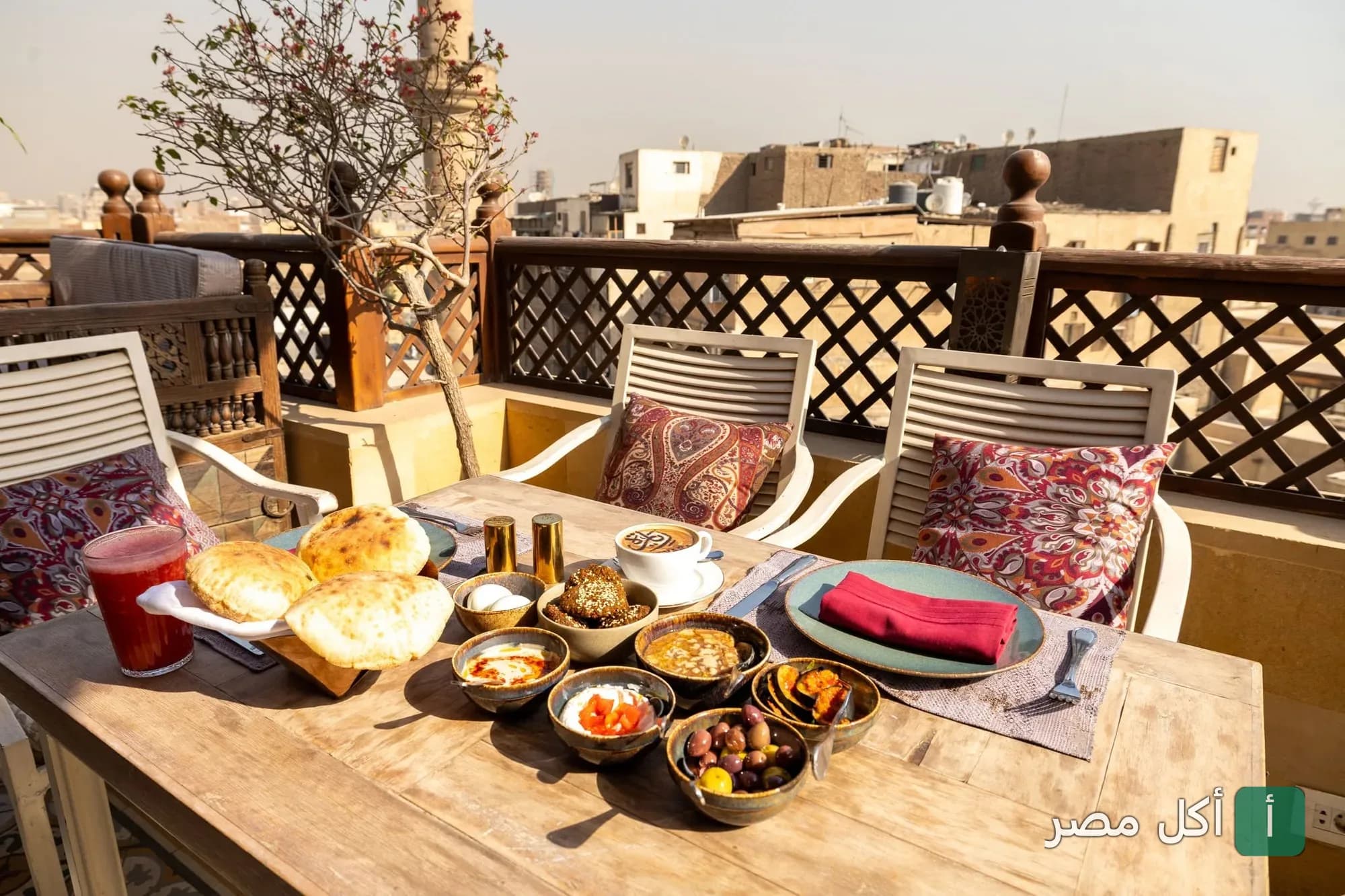 مائدة إفطار مصرية تقليدية في تراس مطعم زيارة المعز بالقاهرة مع إطلالة على المباني التاريخية.