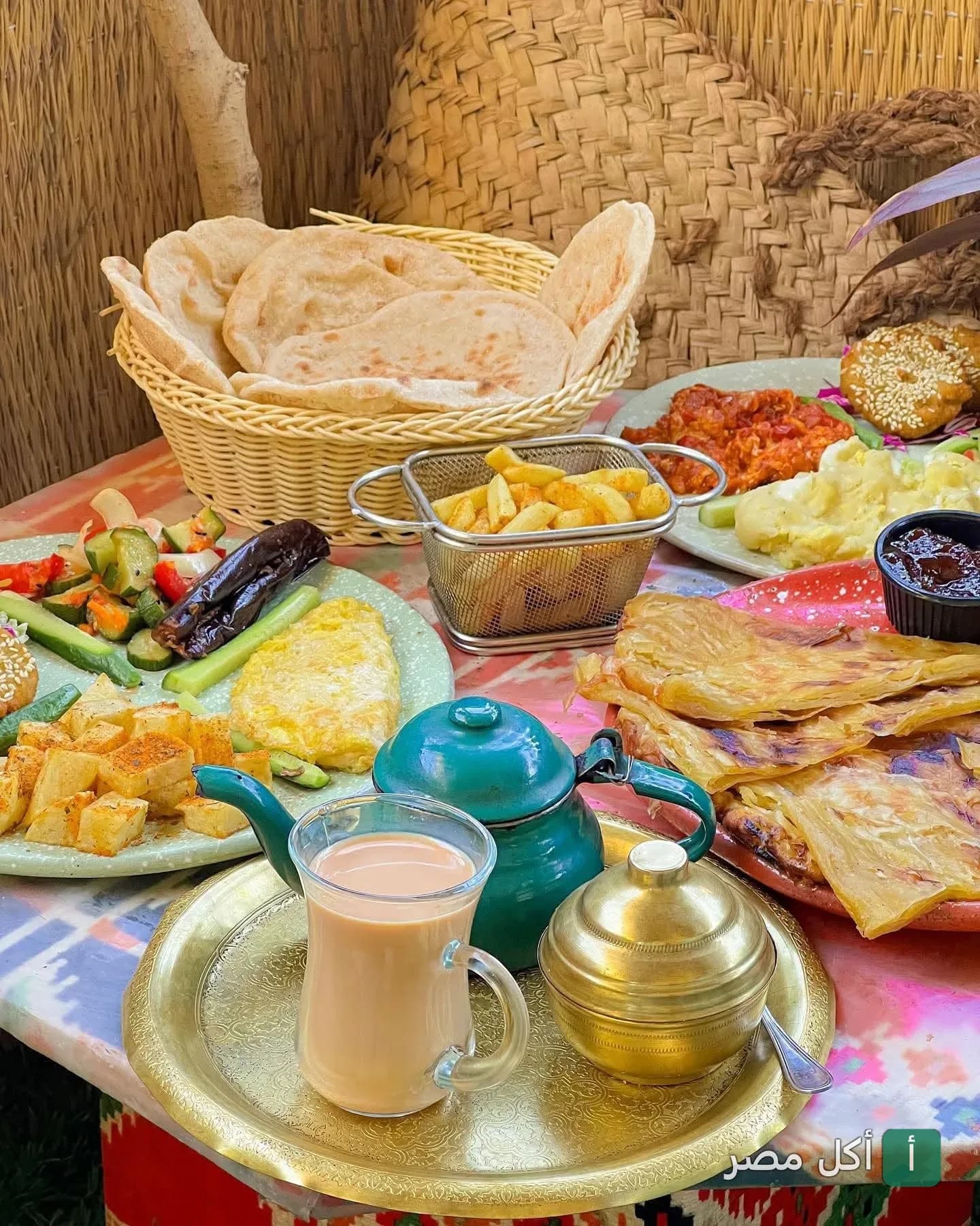 سفرة إفطار شرقي متنوعة في مطعم الكوخ بالقاهرة تضم خبز بلدي، فطير مشلتت، وشاي في إبريق نحاسي.