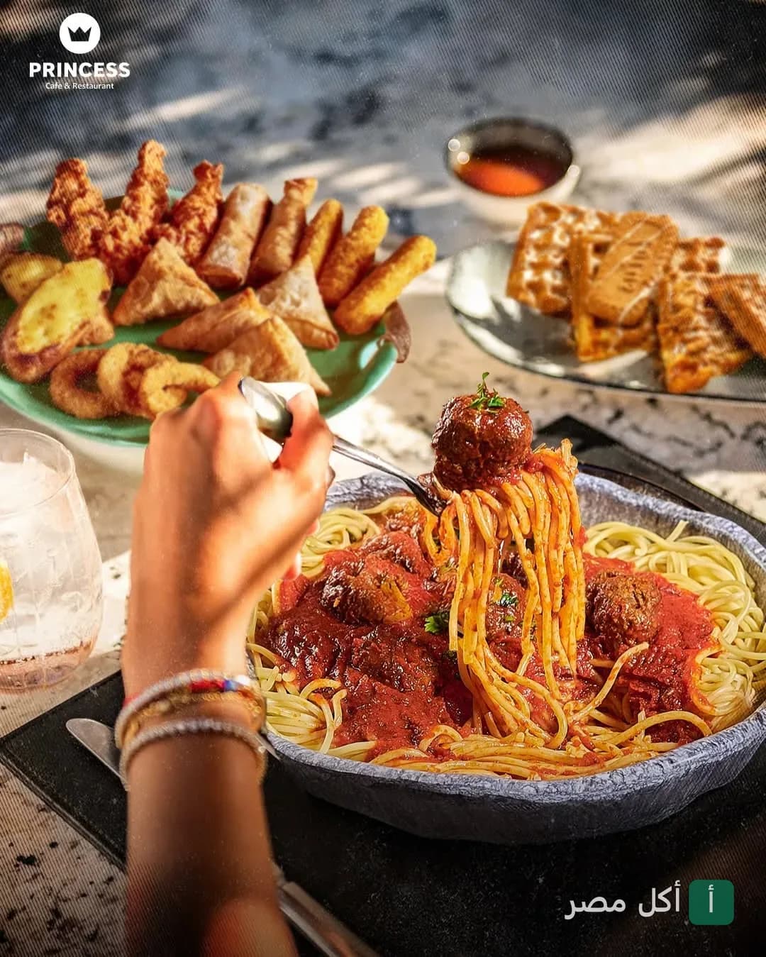 طبق مكرونة بالصلصة وكرات اللحم في مطعم برينسيس بمارينا العلمين مع مقبلات ووافل على الطاولة.