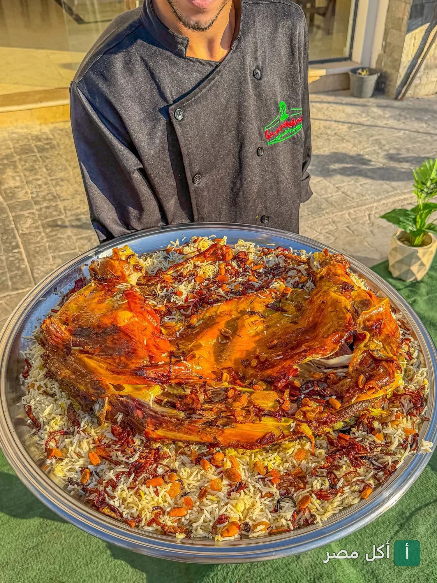 شيف يقدم صينية كبيرة من لحم الضأن المشوي مع الأرز في مطعم مرحبتين ومرحبا بمارينا العلمين.