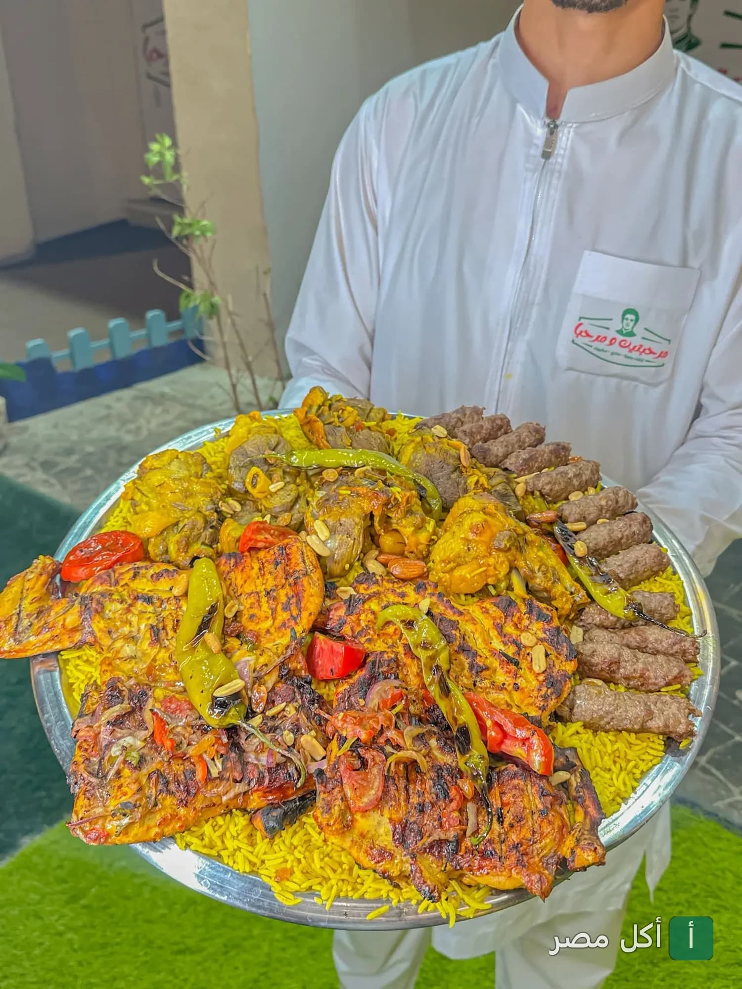 نادل يقدم صينية كبيرة تحتوي على مشاوي مشكلة وأرز في مطعم مرحبتين ومرحبا بمارينا العلمين.