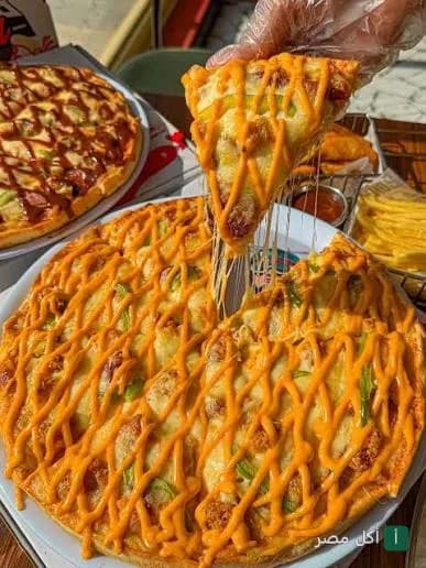 شريحة بيتزا من بريموز بيتزا في مارينا العلمين مع صوص الجبنة السايحة والمطاطية.