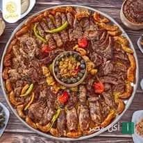 صينية مشويات مشكلة من مطعم منيسي في مارينا العلمين، تحتوي على كباب وكفتة وقطع لحم مع مقبلات.