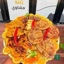 طبق مشاوي مشكل من مطعم رُكنة مشاوي في منيا القمح يضم كفتة وفراخ مشوية مزينة بشرائح البرتقال والفلفل الأحمر.