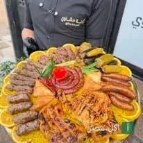 شيف مطعم رُكنة مشاوي يقدم صينية مشويات متنوعة تضم كفتة وسجق ودجاج مشوي مزينة بشرائح البرتقال في منيا القمح.