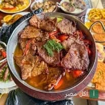 طاجن مشويات متنوعة من مطعم أبو ربيع في منيا القمح، يقدم مع أطباق جانبية.
