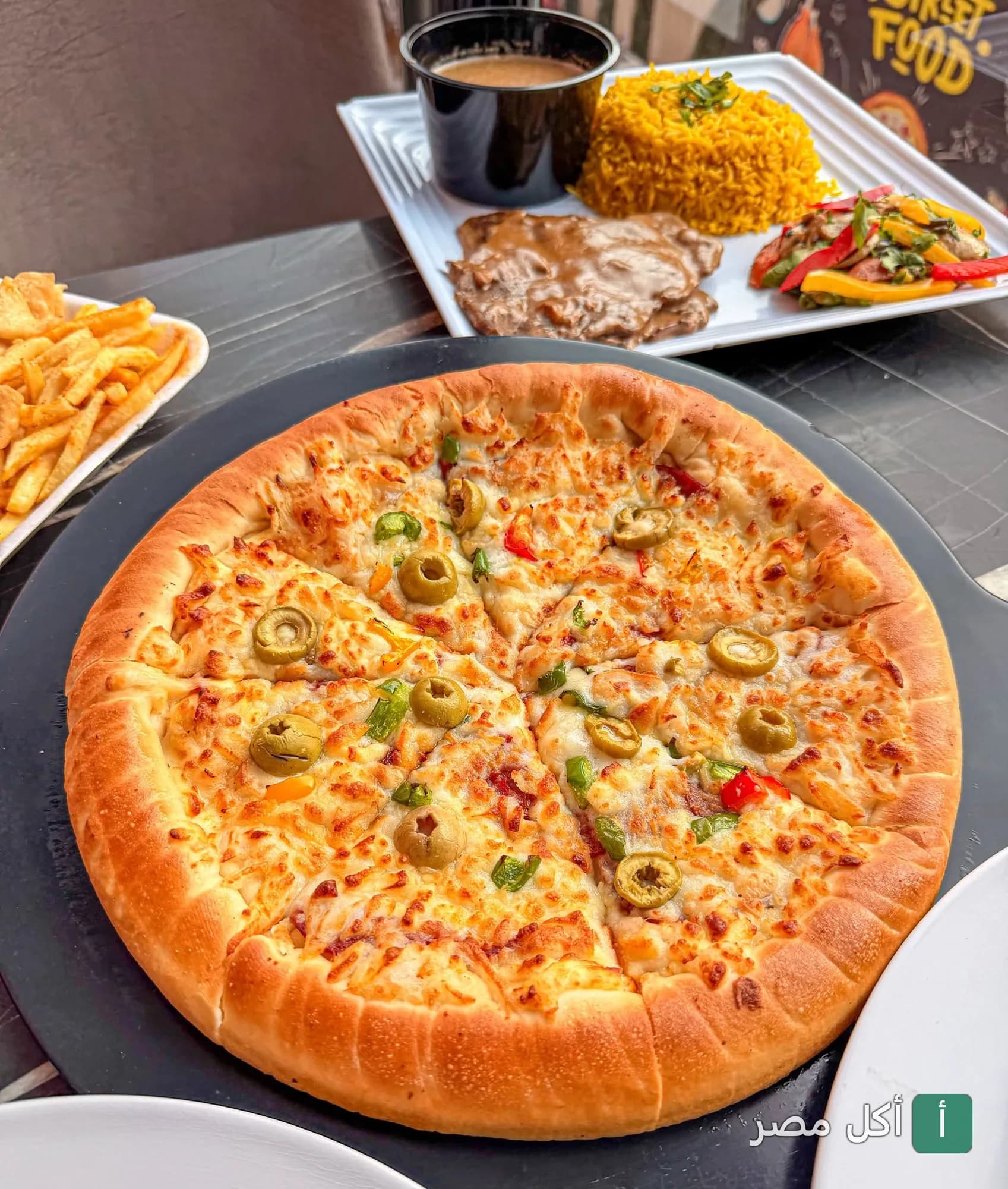 بيتزا بالزيتون والخضار مع طبق أرز وشرائح لحم وبطاطس مقلية من مطعم الثورة بمنيا القمح.