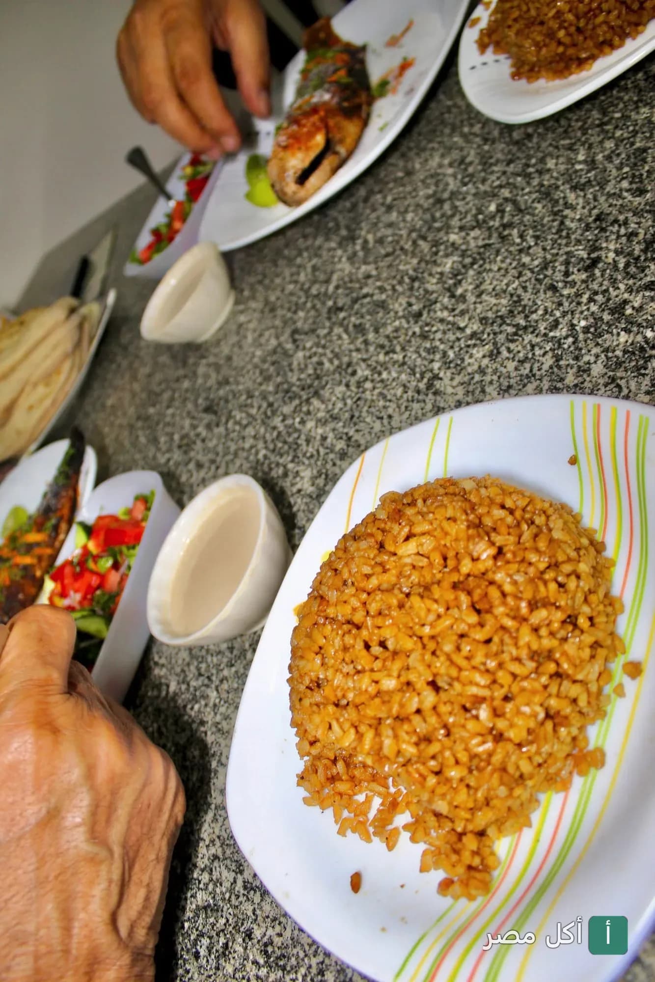 طبق أرز صيادية بجانبه سمك مشوي وسلطة في مطعم استاكوزا بمنيا القمح