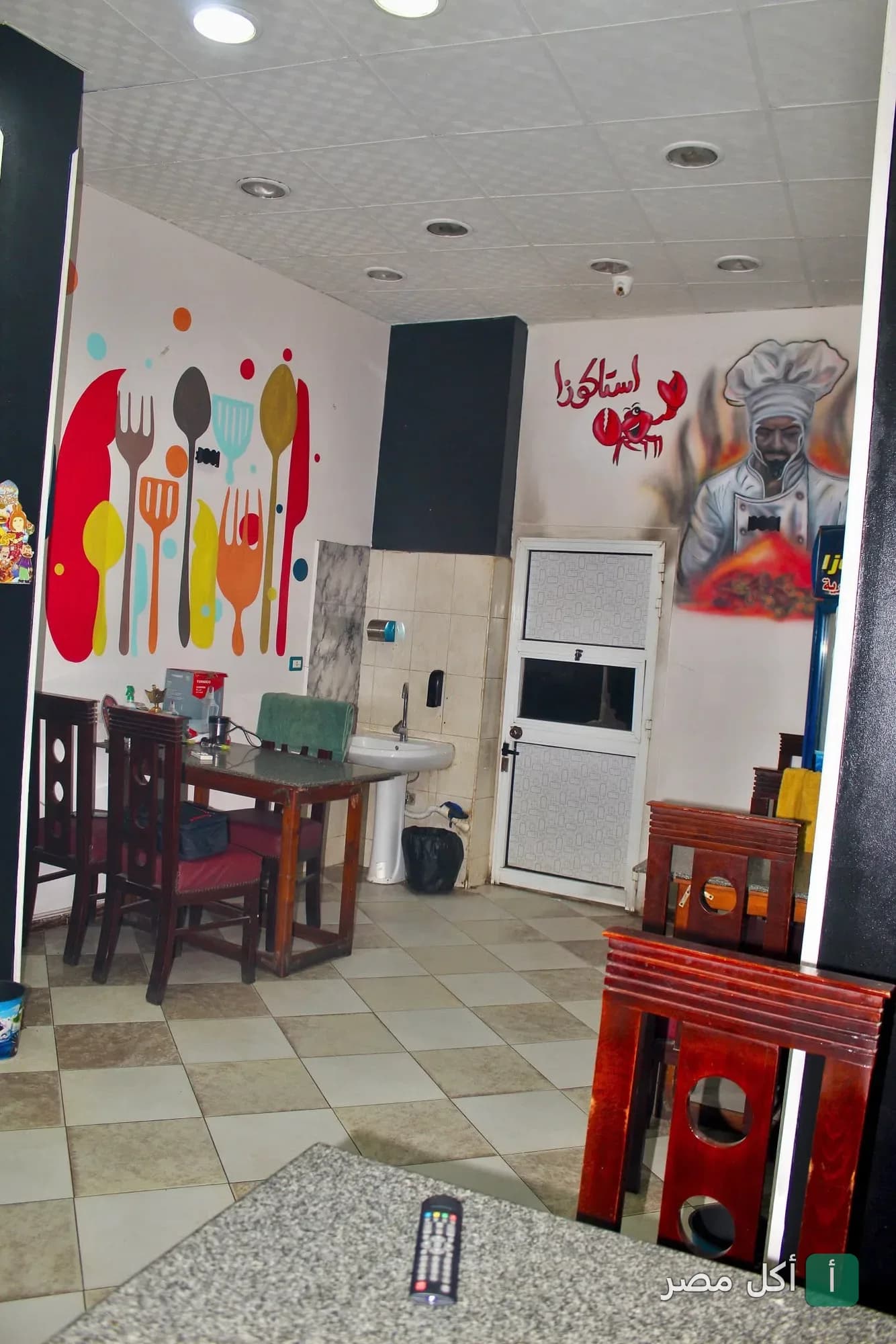 صالة طعام داخل مطعم استاكوزا في منيا القمح، تظهر فيها رسومات جدارية ملونة لأدوات المائدة وشيف، مع طاولات وكراسي خشبية.