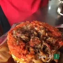 طبق كشري مصري غني بصلصة الطماطم والبصل المحمر من مطعم كشري السندباد في منيا القمح.