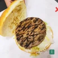 شطيرة برجر مشوية على الجريل في مطعم تشيكن زنجر بمنيا القمح.