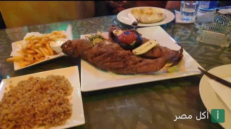 طبق سمك مقلي مع أرز وبطاطس محمرة في مطعم شارك دهب