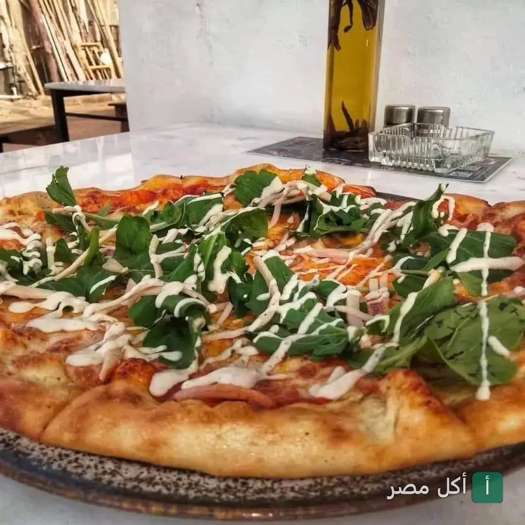 بيتزا بالجرجير والصوص الأبيض على طاولة في مطعم ماما ميا بدهب.