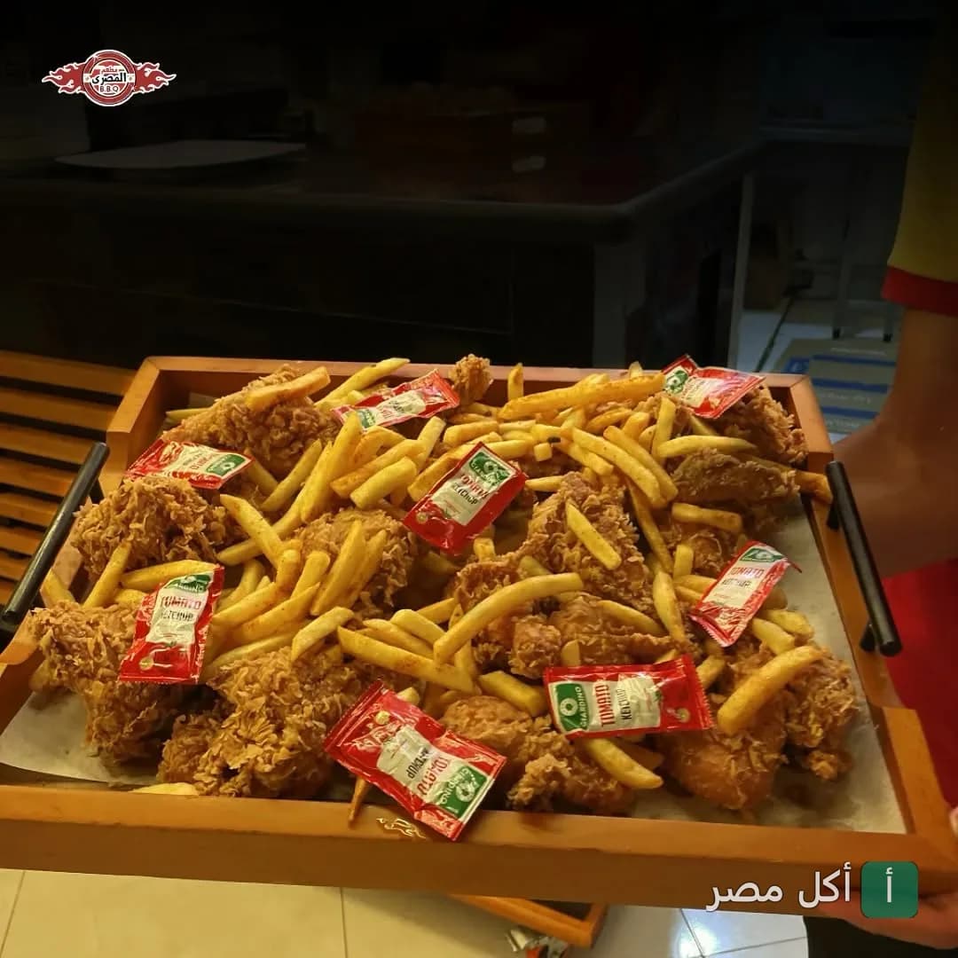 صينية مقليات من مطعم المصري في دهب تحتوي على قطع دجاج مقرمش وبطاطس محمرة مع أكياس كاتشب.