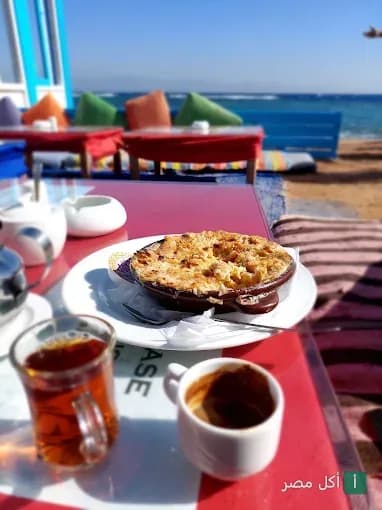 طبق طاجن ساخن مع كوب شاي وقهوة على طاولة مطلة على البحر في مطعم إيل جاردن فيو بدهب.