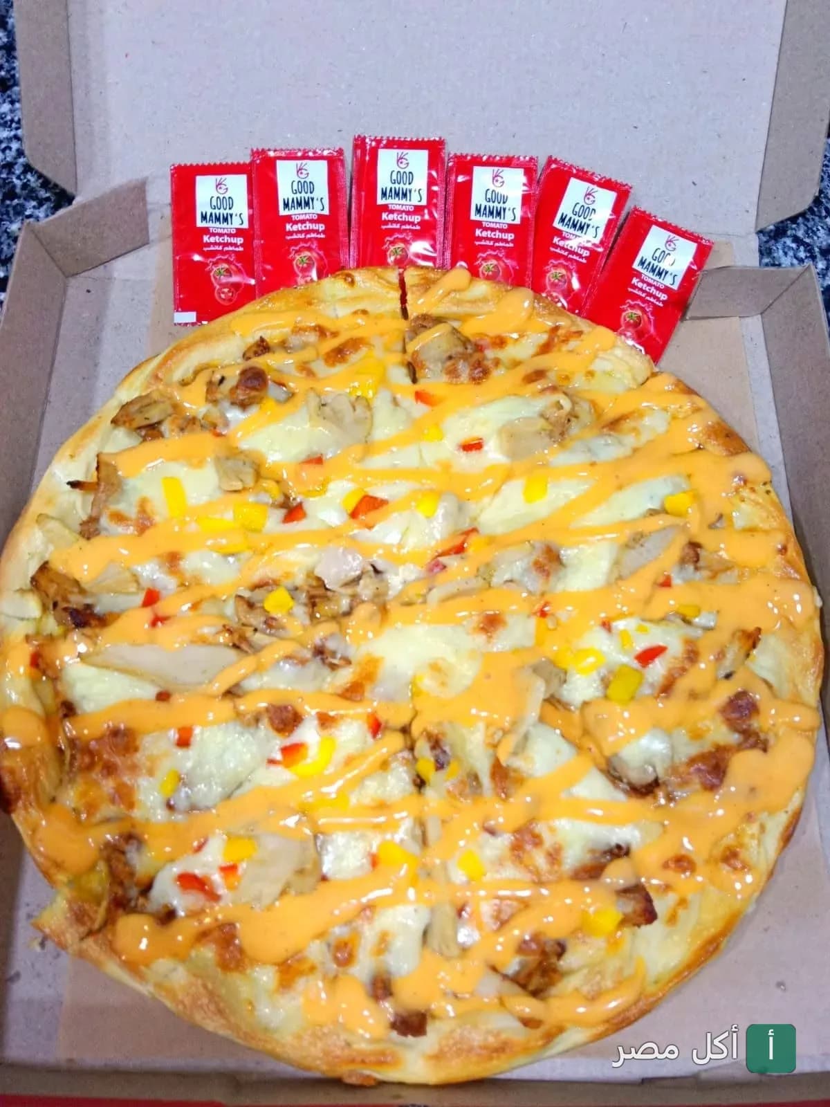 بيتزا دجاج مغطاة بصوص الجبن في علبة كرتون مع أكياس كاتشب من مطعم لودا في 15 مايو.