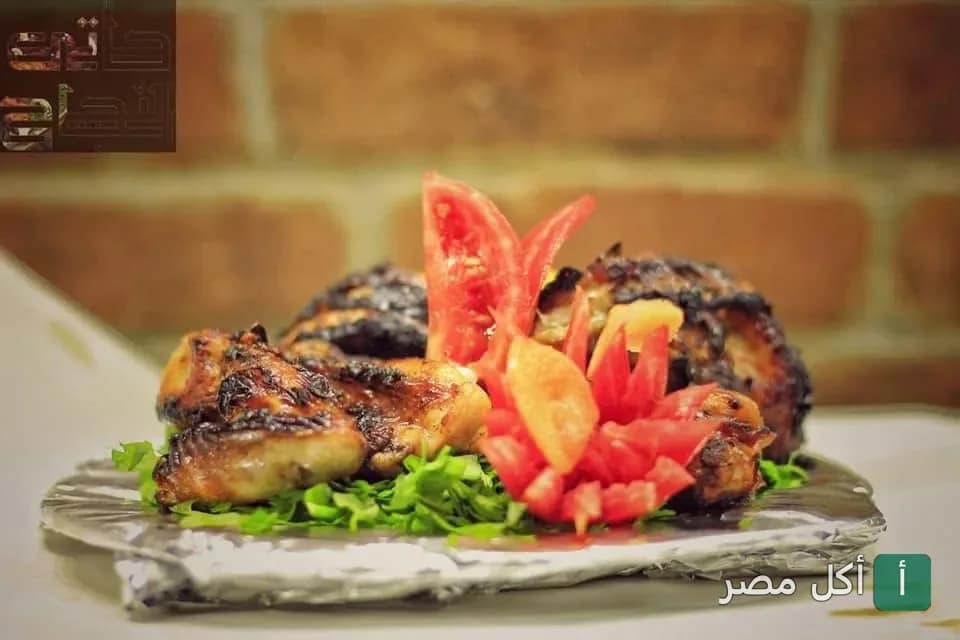 طبق دجاج مشوي على الفحم مزين بالطماطم والبقدونس في مطعم النجاح بالأزبكية