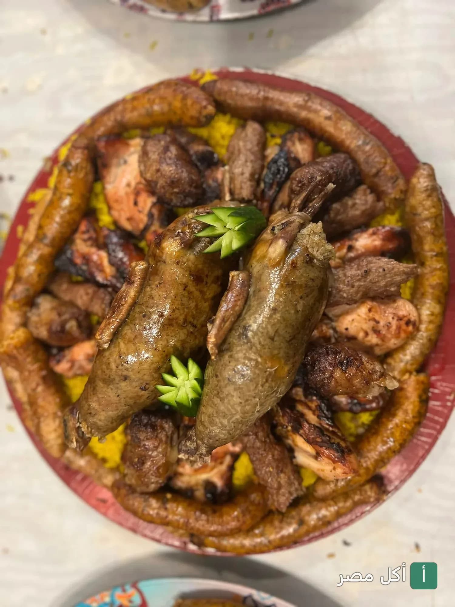 طبق مشويات شرقي من مطعم النجاح بالأزبكية يضم حمام محشي وكفتة وسجق على أرز أصفر.