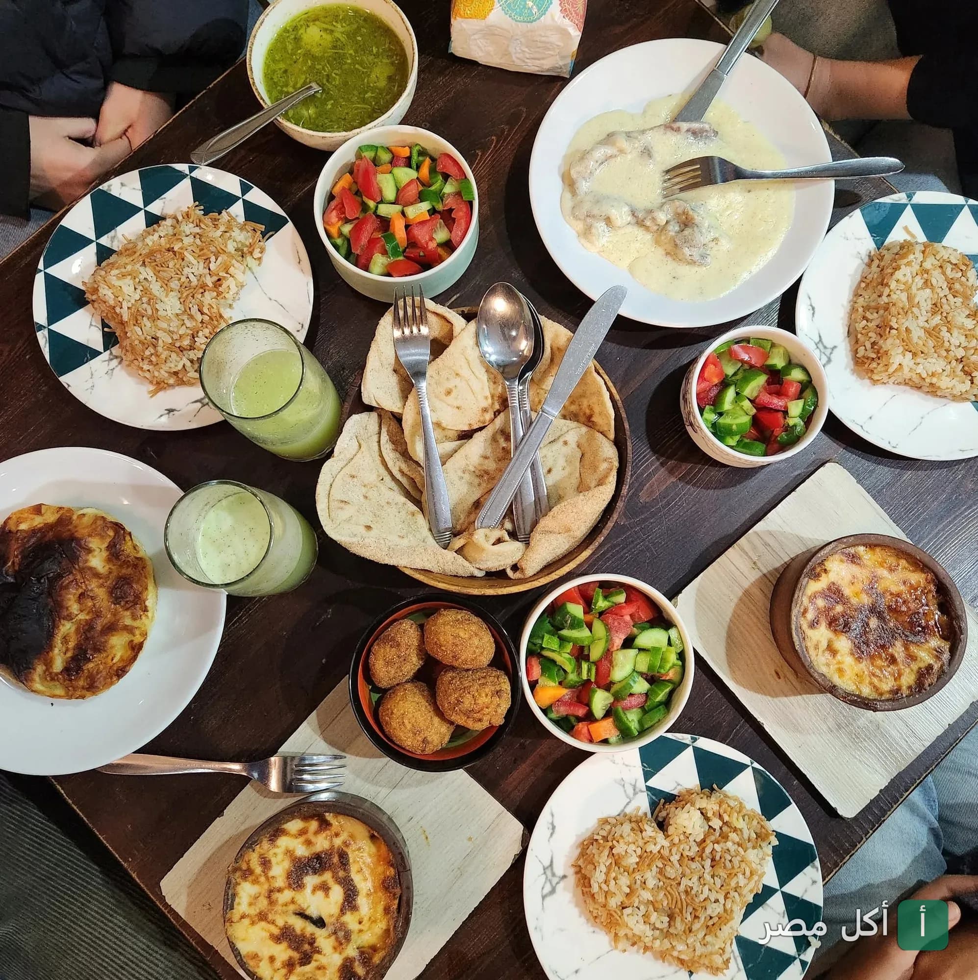 سفرة متنوعة من مطعم طشة بالأزبكية تضم أطباق أرز بالشعيرية، طواجن، سلطة خضراء، ومقبلات شرقية.