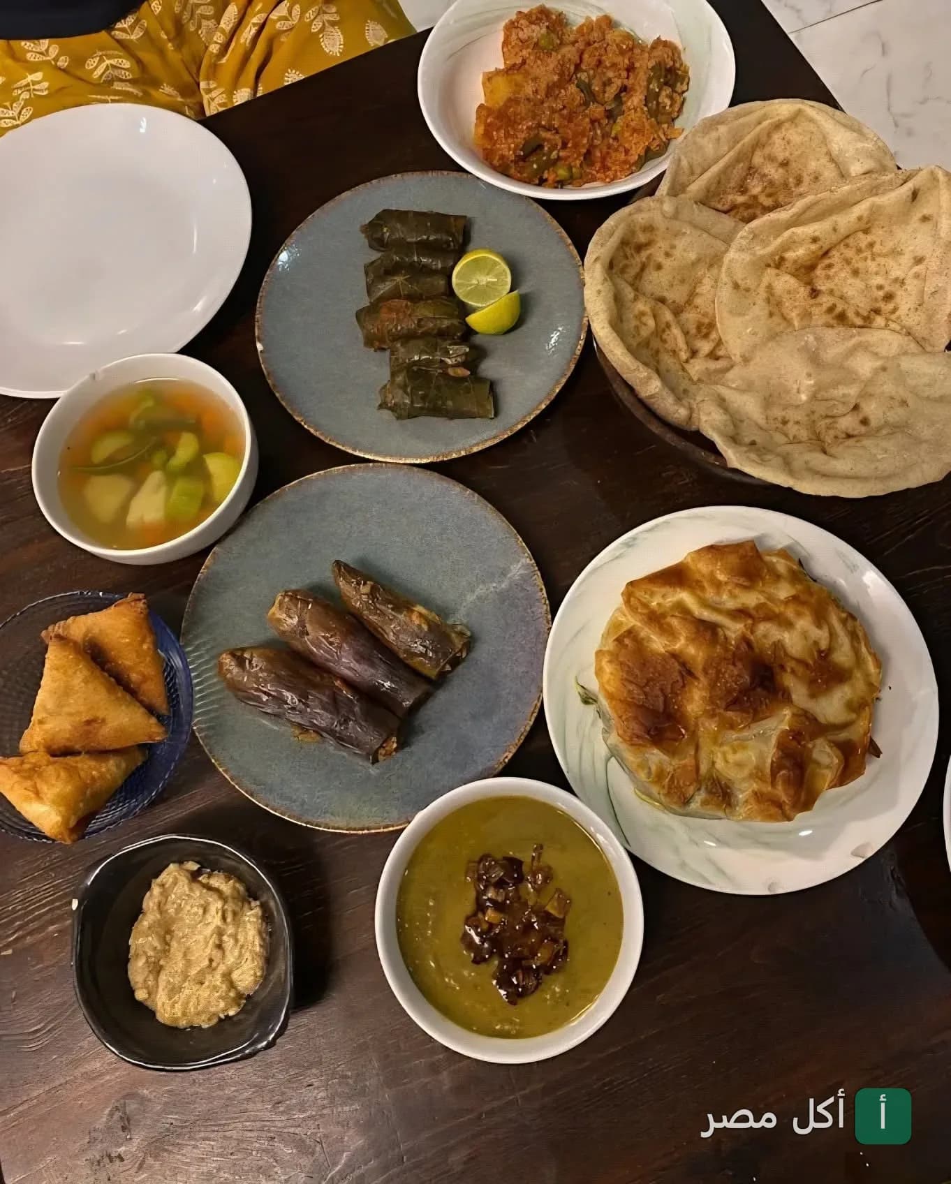 سفرة مصرية متنوعة تضم محشي ورق عنب، باذنجان، ملوخية، وفطير في مطعم طشة بالأزبكية.