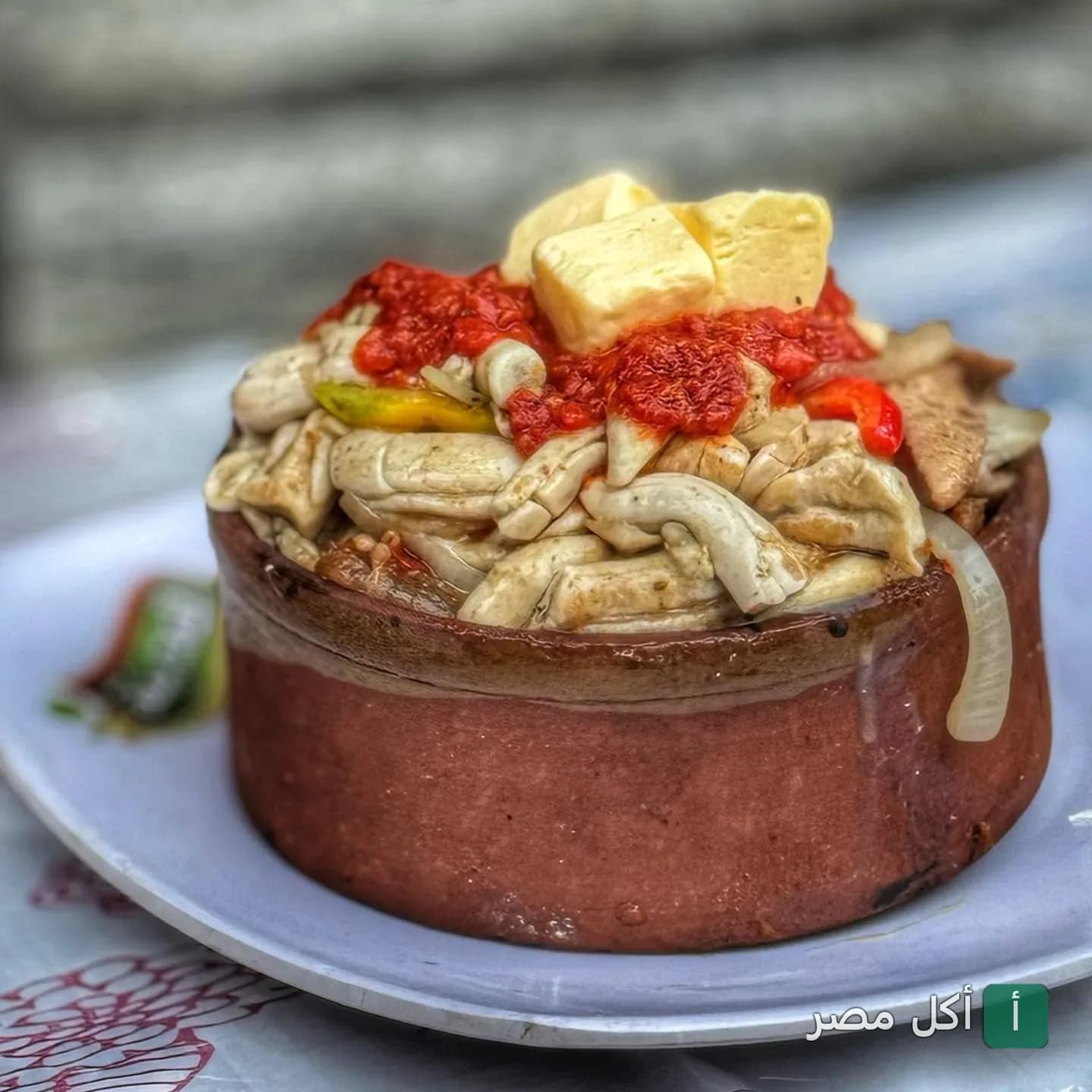 طاجن شرقي من مطعم المدينة في الأزبكية يقدم في فخارة تقليدية مع قطع الزبدة والصلصة.