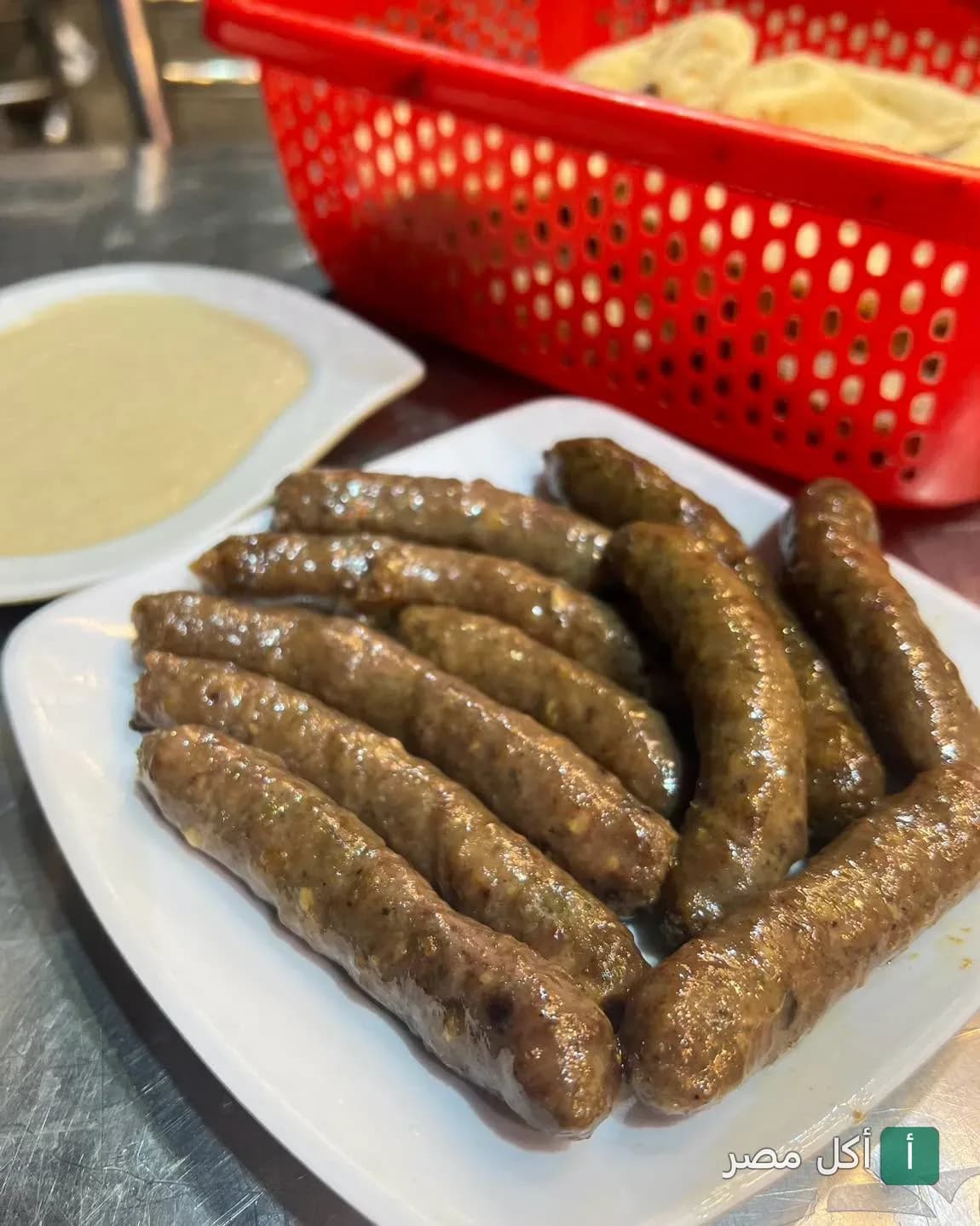 طبق سجق مشوي يقدم مع الطحينة والخبز في مطعم المدينة بالأزبكية