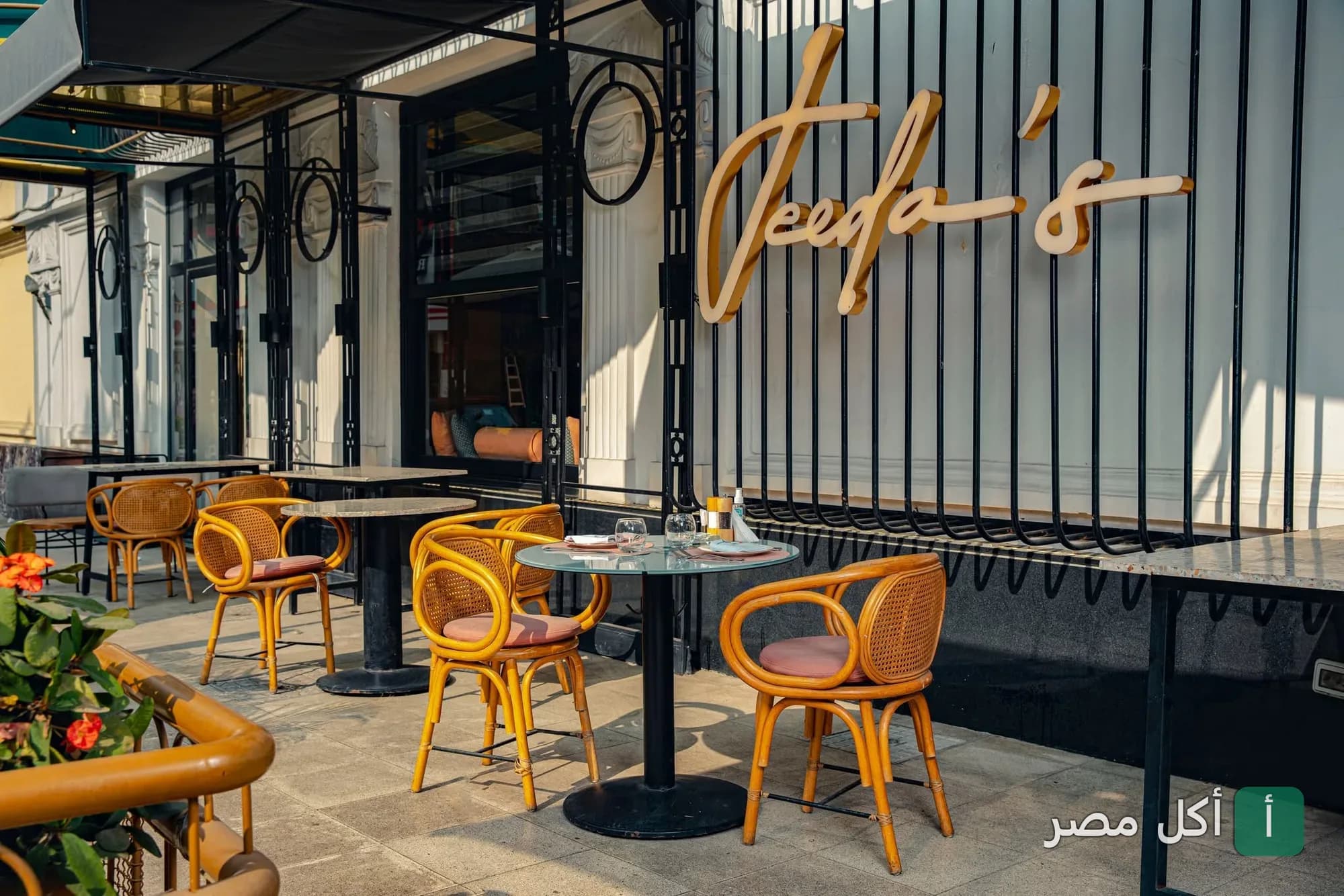 جلسات خارجية أنيقة أمام مطعم جيدة في الإسكندرية مع لافتة المطعم الذهبية.
