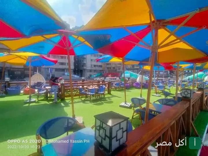 جلسات خارجية في مطعم SeaSide بالإسكندرية مع شمسيات ملونة وأرضية عشب صناعي.