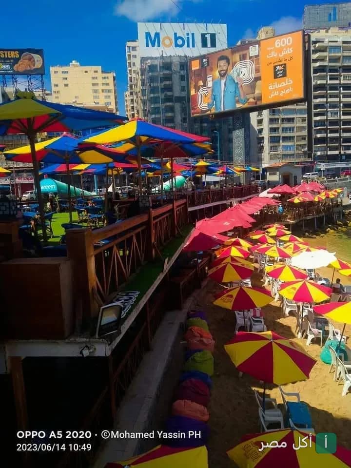 جلسات خارجية ملونة بمظلات على الشاطئ في مطعم SeaSide بالإسكندرية.