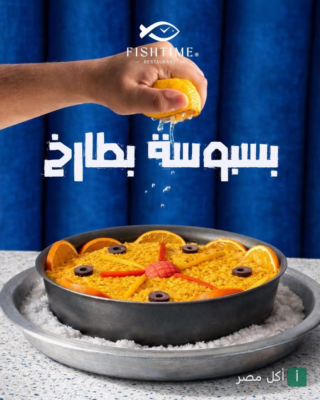 يد تعصر ليمون فوق طبق أرز مزين بالزيتون وشرائح البرتقال في مطعم فيش تايم بالبساتين.