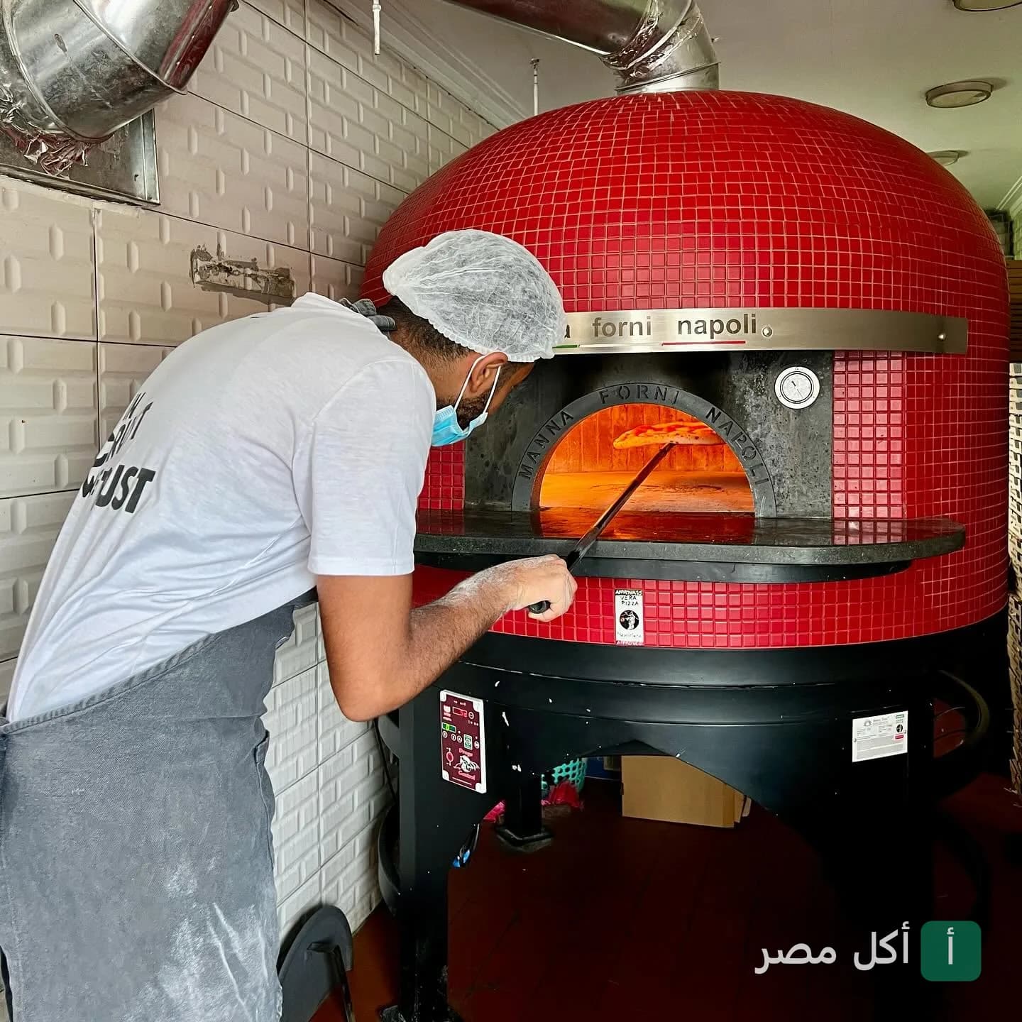 شيف يخبز بيتزا في فرن نابولي أحمر في مطعم وات ذا كرست بالبساتين.