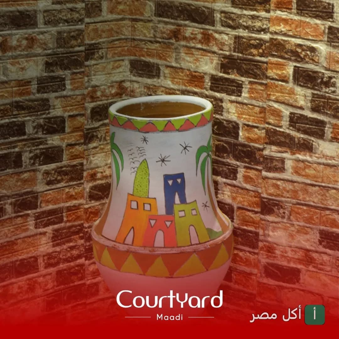 زينة فخارية مرسوم عليها بيوت ونخيل في مطعم كورت يارد المعادي