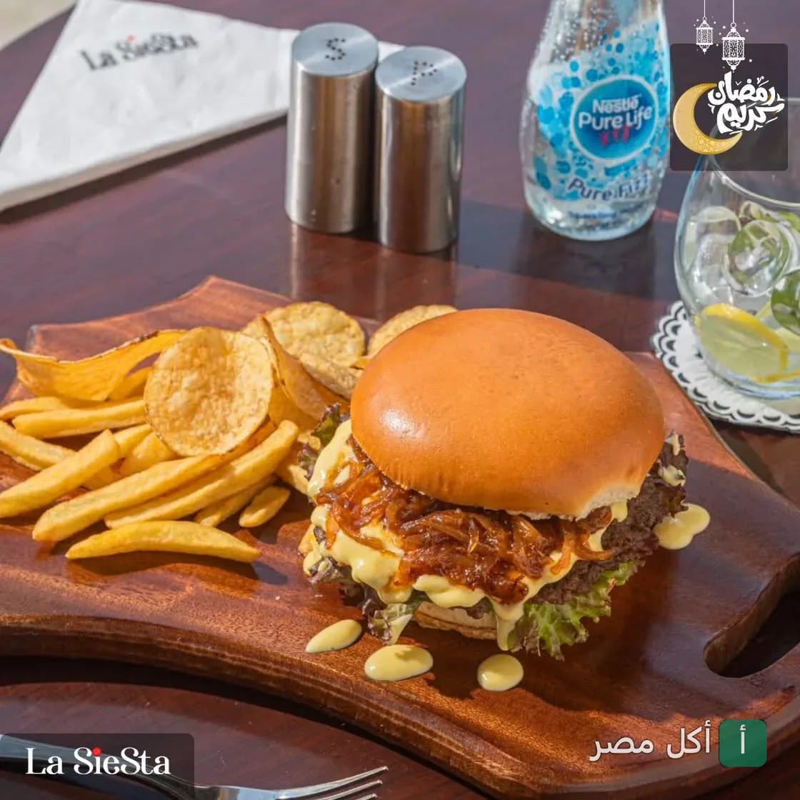 ساندوتش برجر مع بطاطس محمرة على لوح خشبي في مطعم لاسيستا بالبساتين.