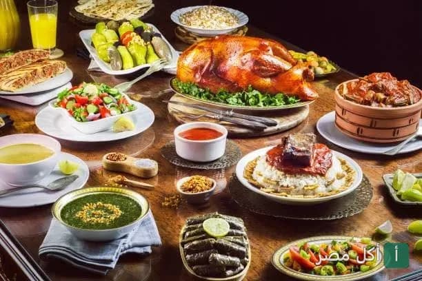 سفرة طعام مصرية متنوعة تضم دجاج مشوي، فتة، محشي ورق عنب، وملوخية في مطعم بلدينا بالبساتين.