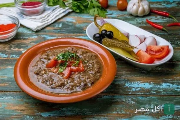 طبق فول مدمس في مطعم بلدينا بالبساتين مع مقبلات من المخلل والخضروات الطازجة.