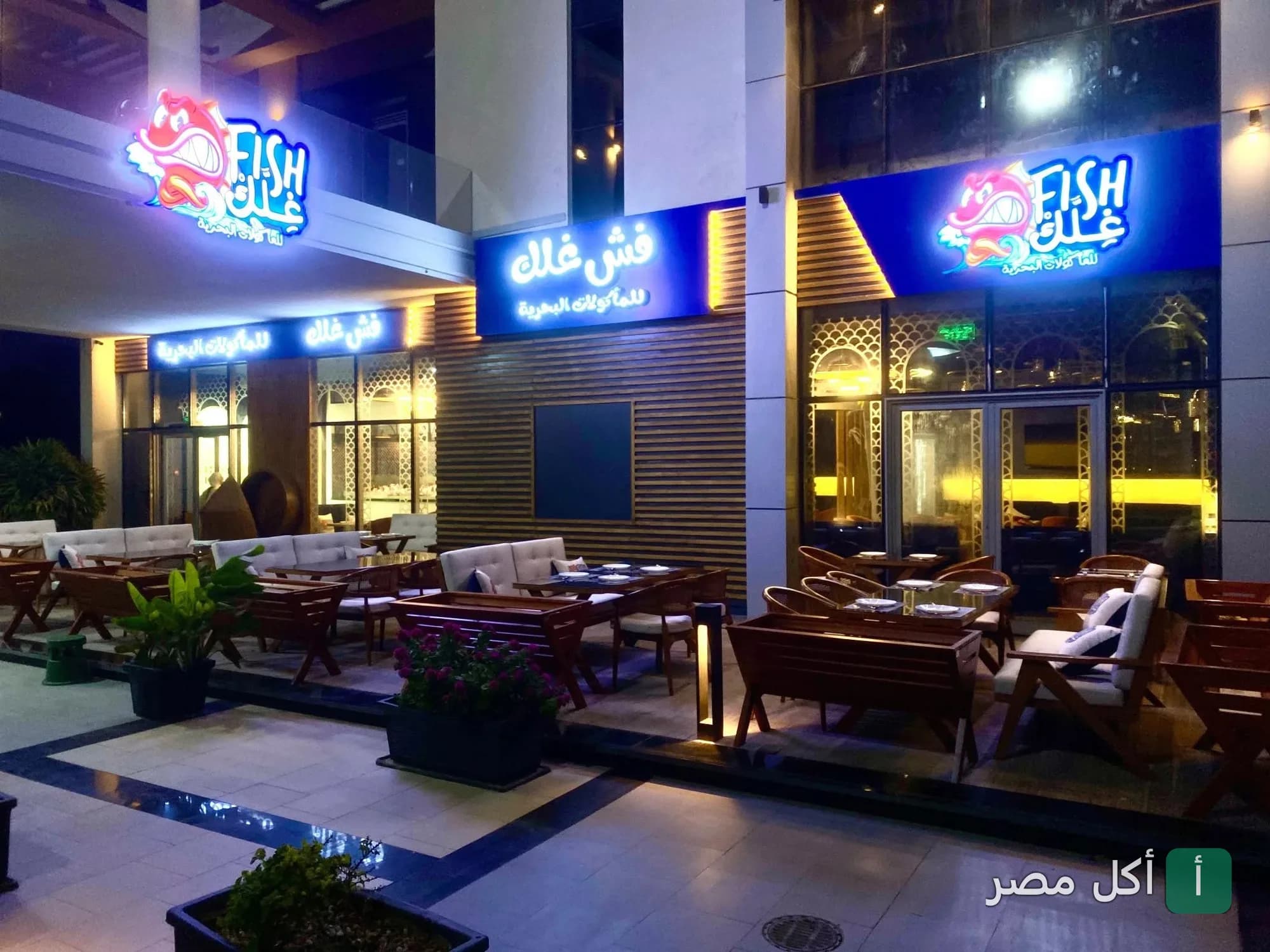 واجهة مطعم فش غلك للمأكولات البحرية في البساتين مع جلسات خارجية مضيئة.