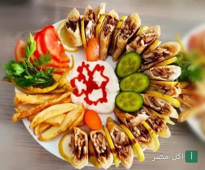 طبق شاورما دجاج مقطع مع بطاطس محمرة، خيار، طماطم، وصوص الثومية في مطعم البيت السوري بالبساتين.