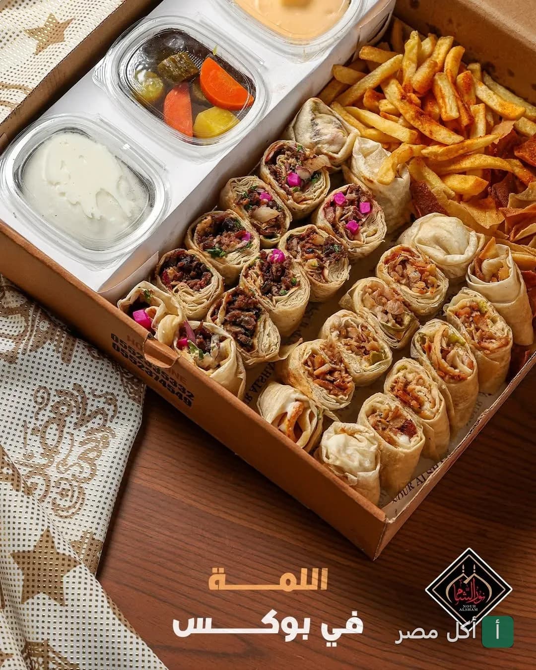 وجبة عائلية من مطعم نور الشام في الزقازيق تحتوي على ساندوتشات شاورما سورية مقطعة مع بطاطس مقلية ومقبلات.