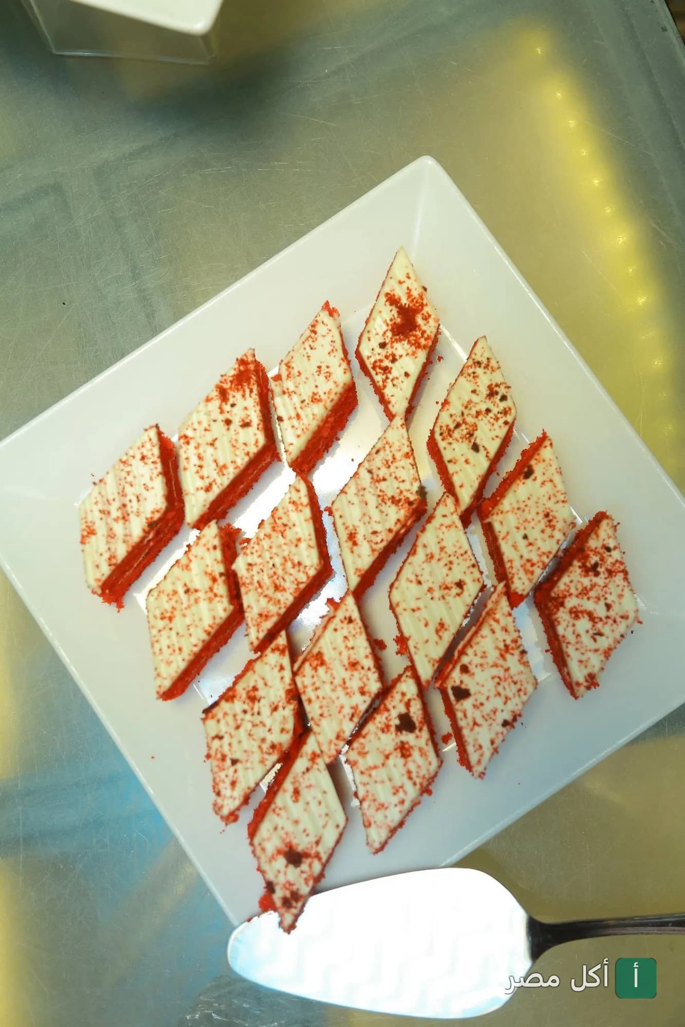 قطع حلويات حمراء مغطاة بطبقة بيضاء على طبق أبيض في مطعم نايل فاروز كروزنج بالجيزة.