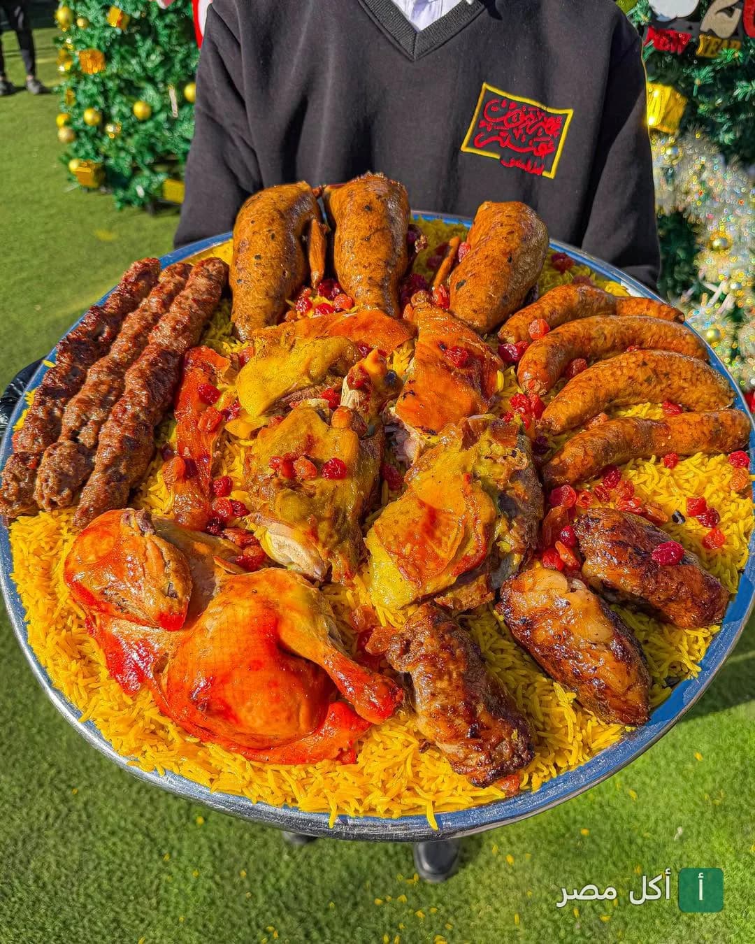 صينية مشويات حضرموت عنتر الكبيرة تحتوي على أرز ومشاوي متنوعة يقدمها موظف المطعم في فرع القاهرة الجديدة.