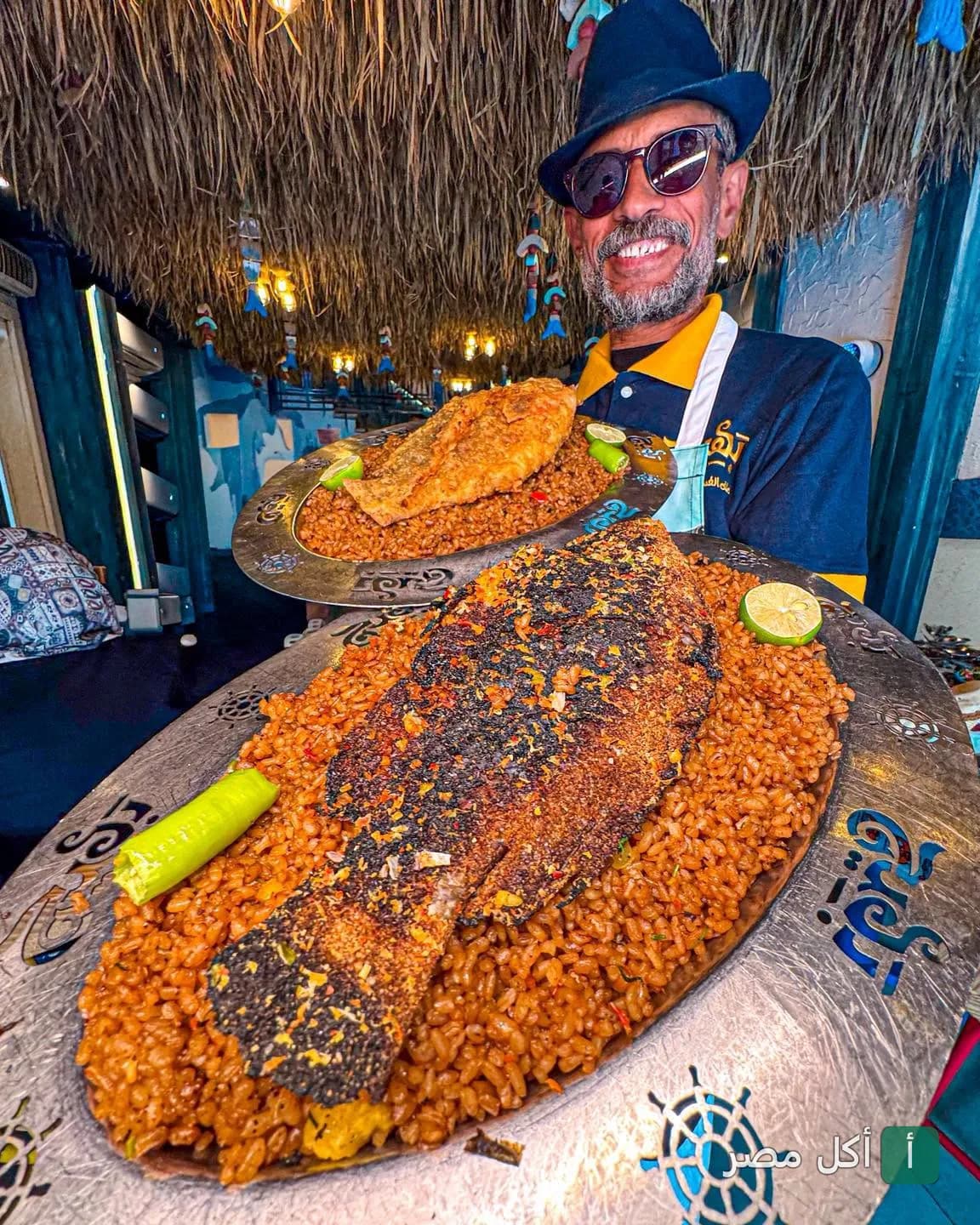 شيف مطعم بهيج يقدم أطباق السمك المشوي مع الأرز الصيادية في مطعم المأكولات البحرية.