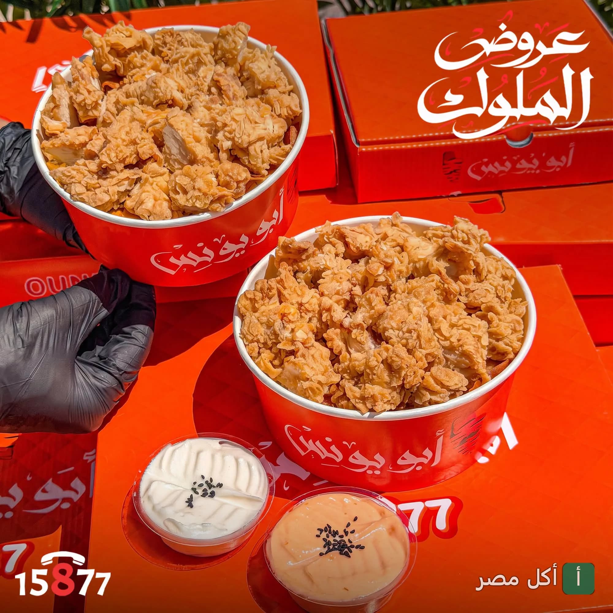وجبات دجاج مقرمش في علب حمراء تحمل شعار مطعم أبو يونس بالبيطاش مع صوصات جانبية.