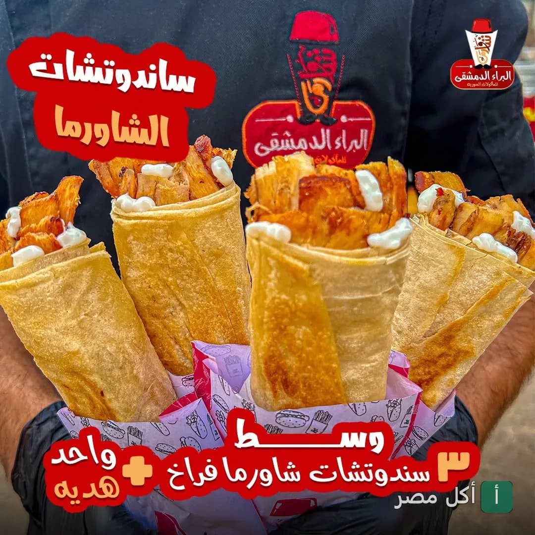 شخص يمسك أربع سندوتشات شاورما فراخ في مطعم البراء الدمشقي 2 بالعامرية.