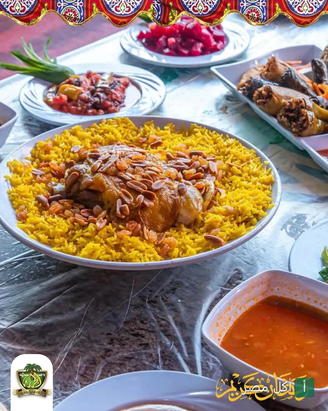 طبق أرز أصفر بالمكسرات مع الدجاج في مطعم واحة الجراري 2 بالعامرية، يحيط به أطباق جانبية من المحاشي والمقبلات.