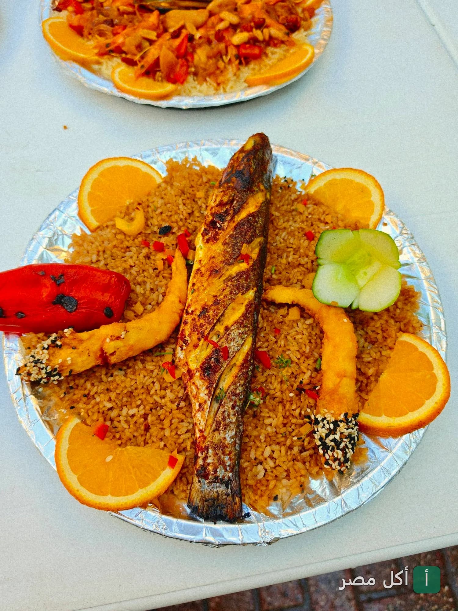 طبق سمك مشوي مع أرز صيادية ومقبلات في مطعم أسماك الزفر بالعامرية.